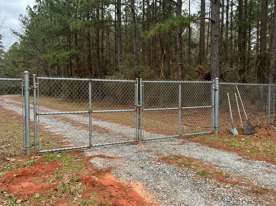 A galvanized chain link double drive gate across a gravel driveway