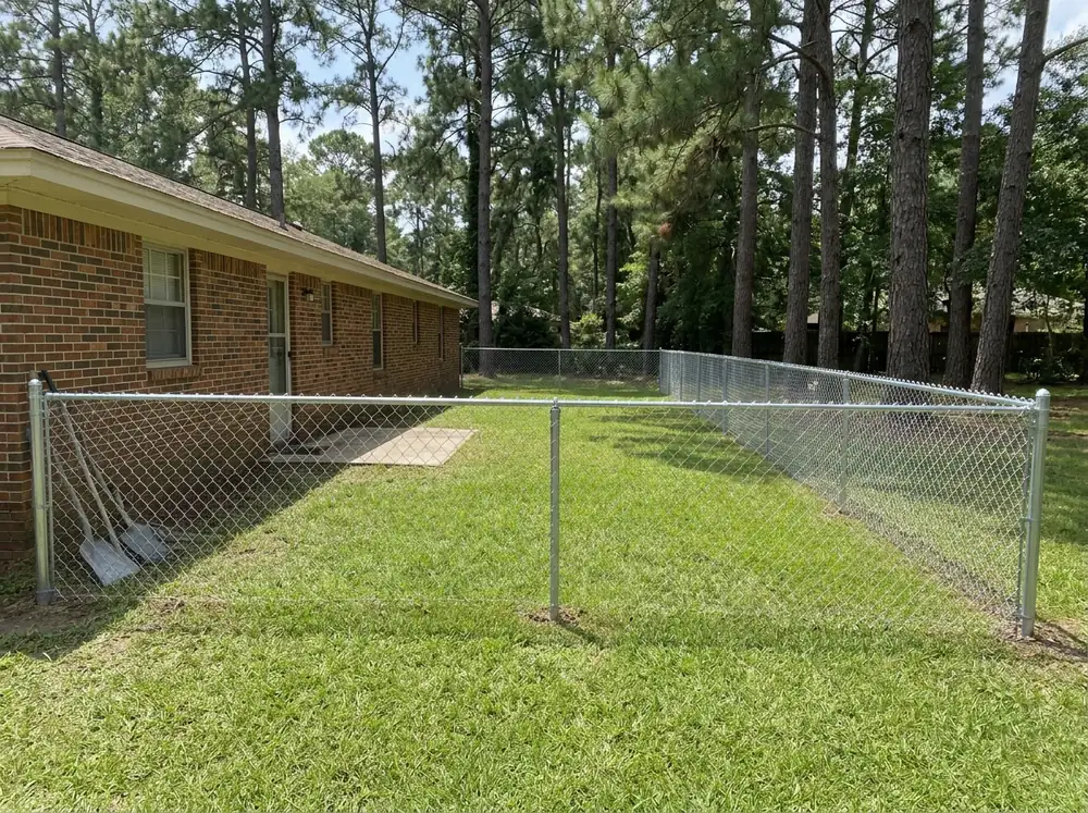 A 4-foot galvanized chain link fence with a top rail around a grassy backyard