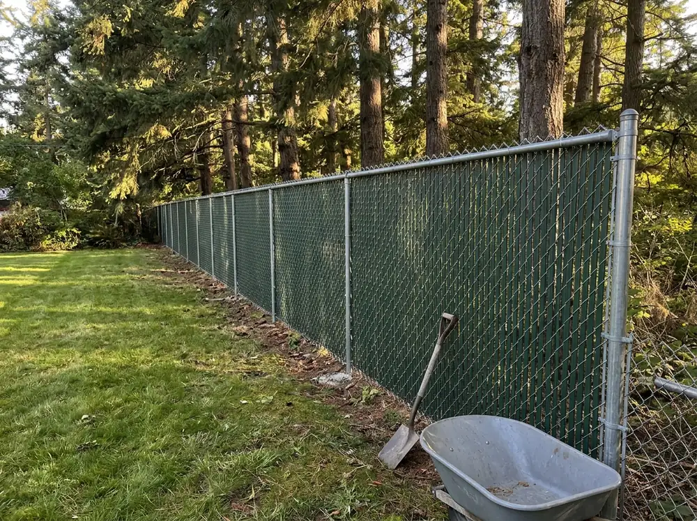 A 6-foot chain link fence with green privacy slats woven through the mesh