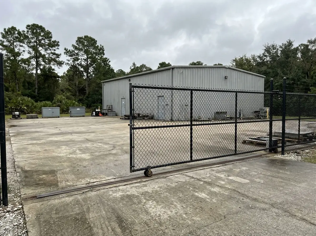 Black vinyl-coated rolling chain link gate across a loading yard entrance