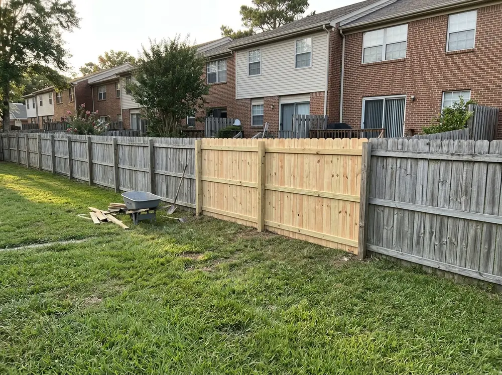 New wood privacy fence section built to match the older neighboring sections behind townhomes