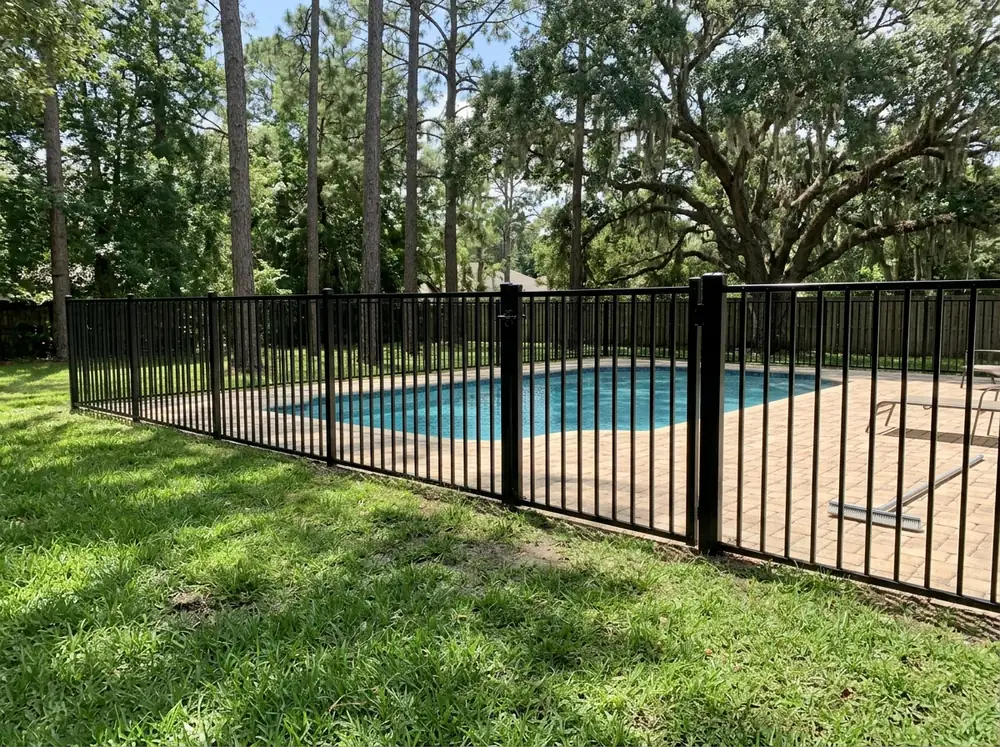 A 4-foot black aluminum pool fence with flat tops around a pool with a paver deck