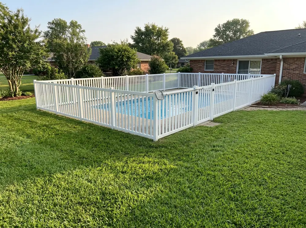 A white vinyl pool fence with closely spaced pickets around a backyard pool