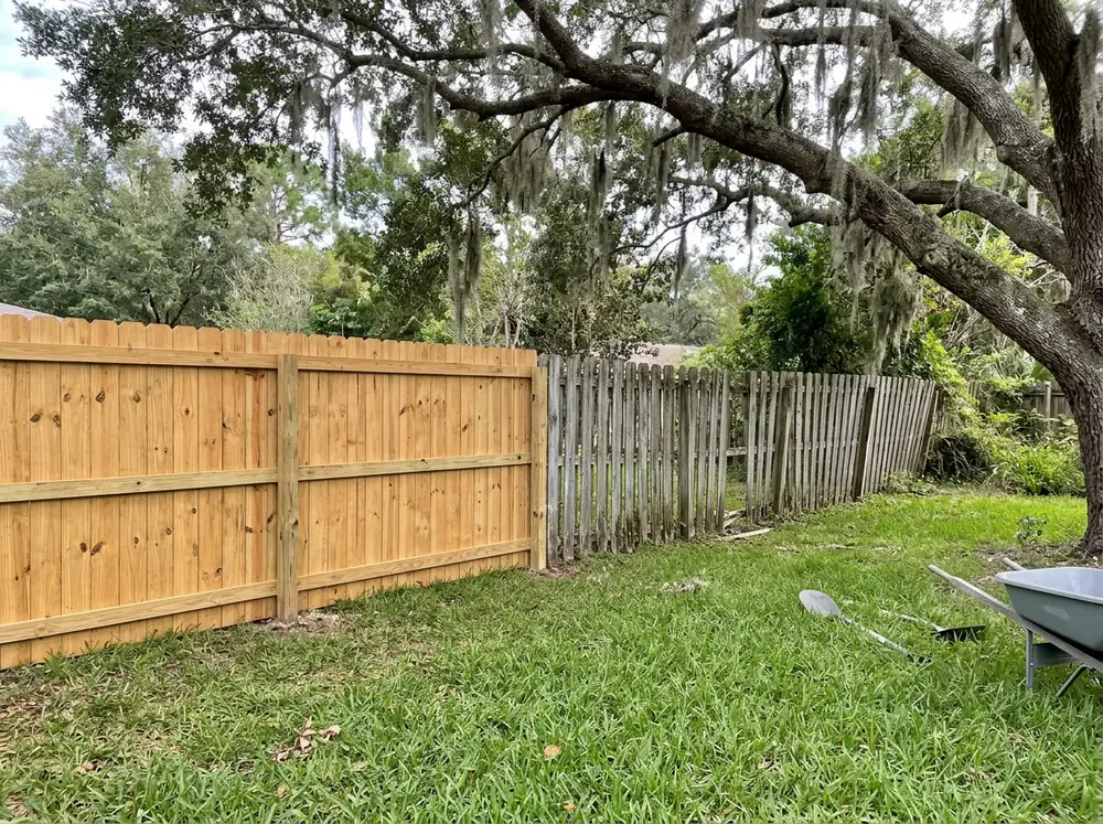A new pine privacy fence section meeting a gray, leaning old section that is next to come down