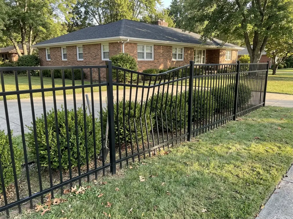 A black aluminum fence section with bent pickets next to straight undamaged sections