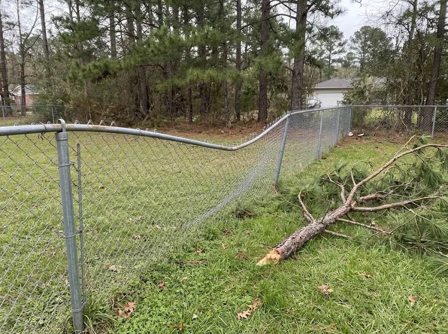 A chain link fence with a bent top rail and sagging mesh waiting for repair