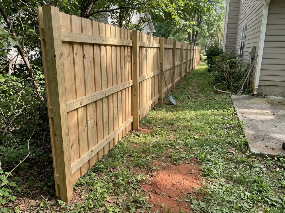 A shadowbox wood fence with boards alternating on both sides of the rails along a side yard